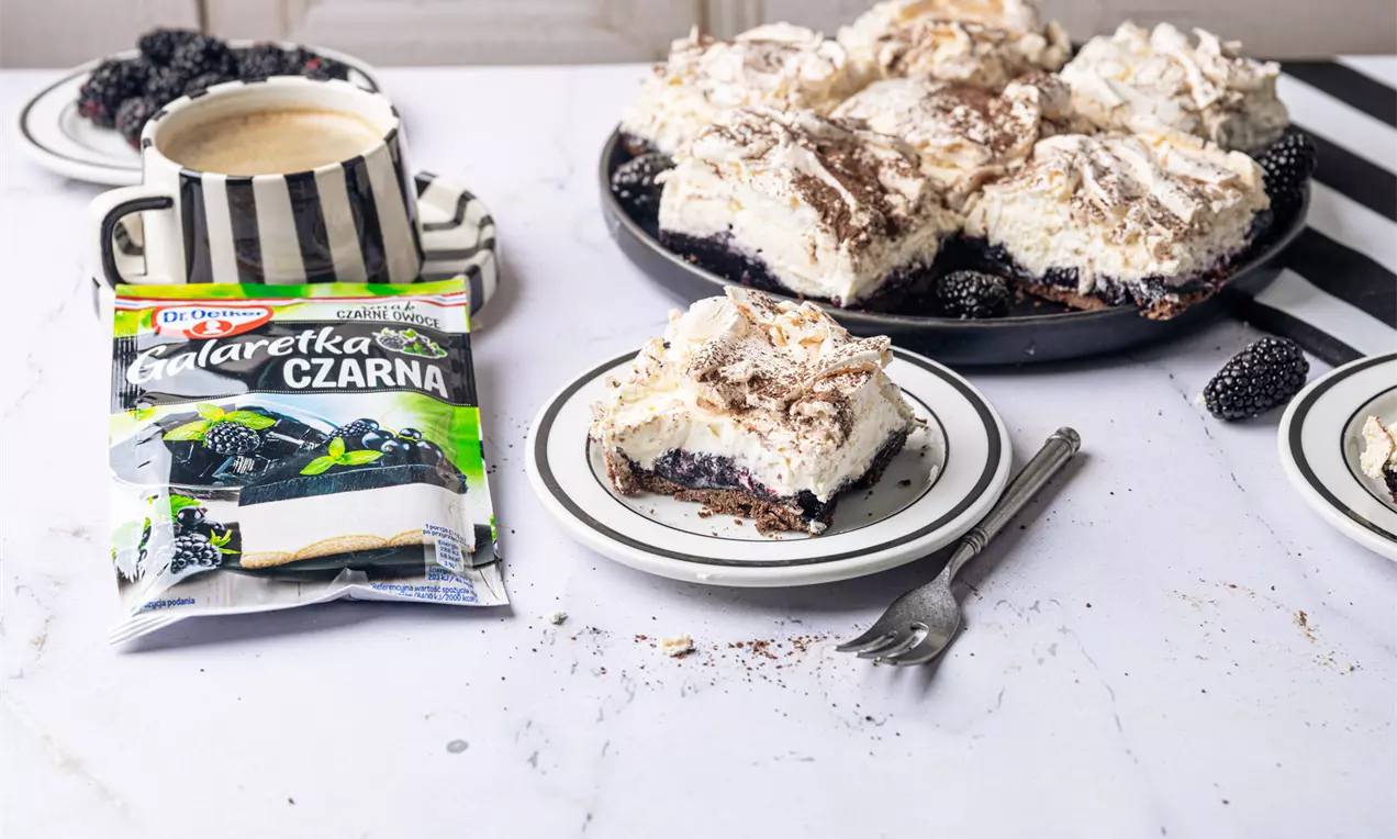 Porzeczkowa Chmurka z ciemnym spodem, warstwą galaretki, puszystą pianką i posypką, na talerzu obok jeżyn i filiżanki kawy