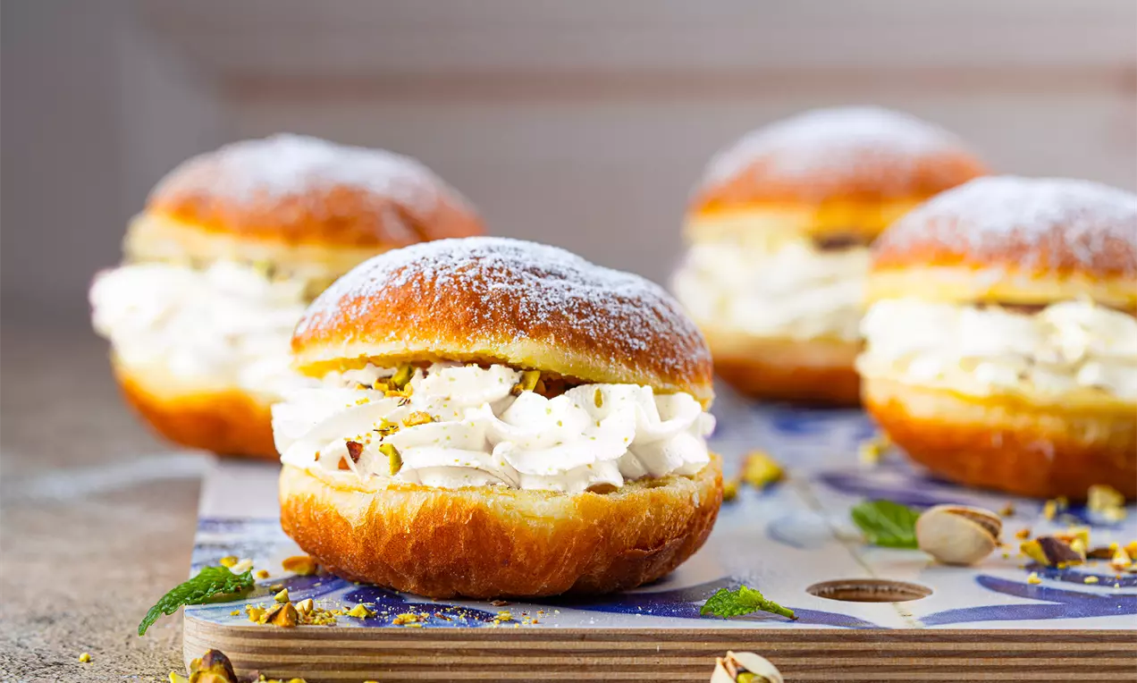 Zdjęcie przedstawia Puszyste Pączki z kolorową bitą śmietaną